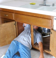 Plumber working under sink